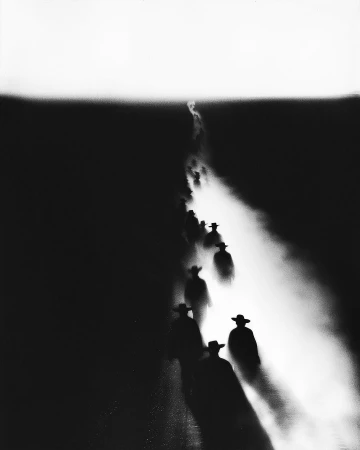 Monochrome image showcases a group of silhouetted figures wearing cowboy hats, walking on a dusty trail with a strong backlight effect.