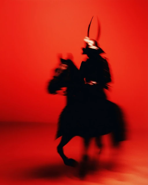 Silhouette of a samurai warrior on horseback in motion against a vivid red background, evoking a sense of ancient Japanese martial arts.