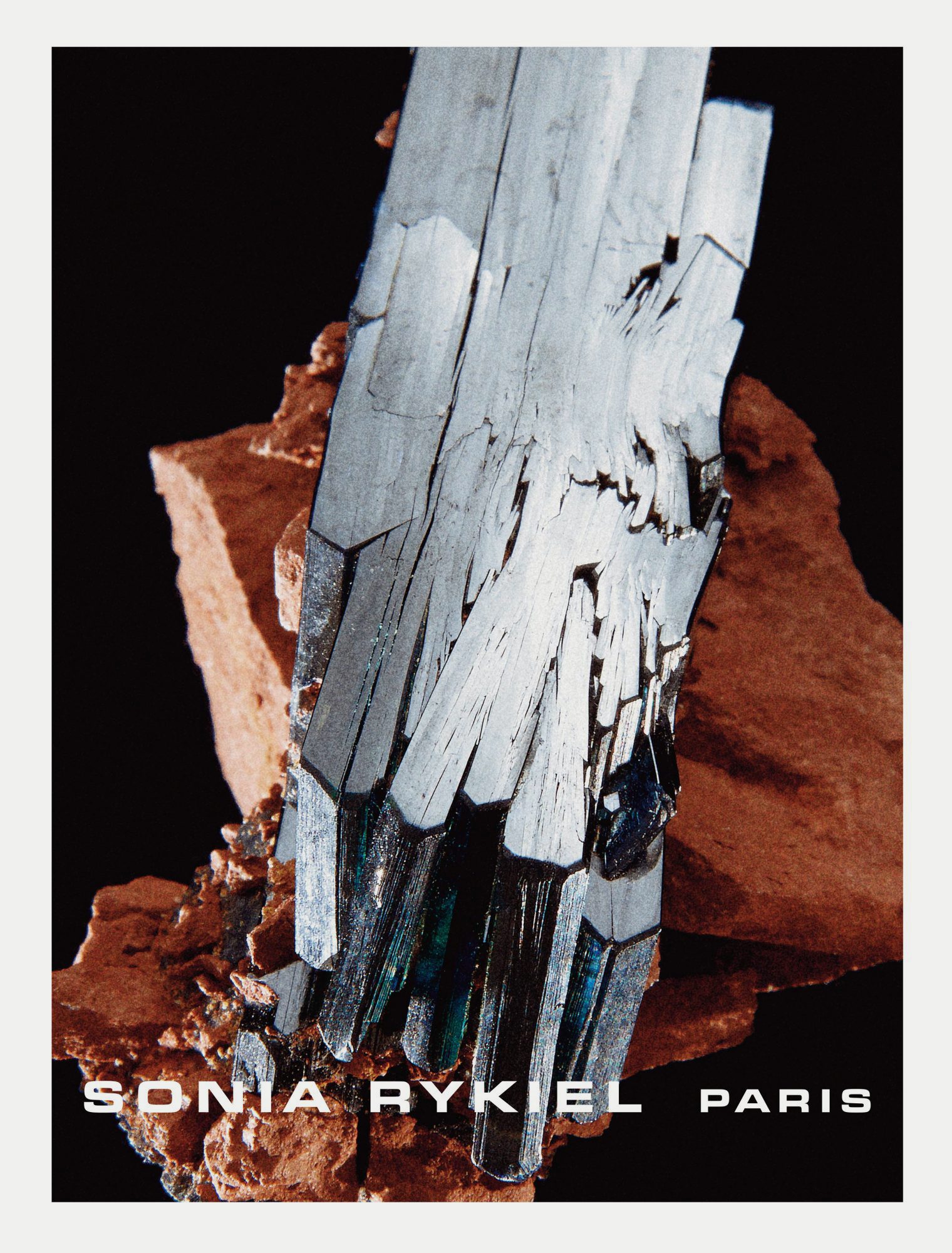 Textured silver crystal formation against dark backdrop, with 'SONIA RYKIEL PARIS' text adding brand and location detail to the composition.