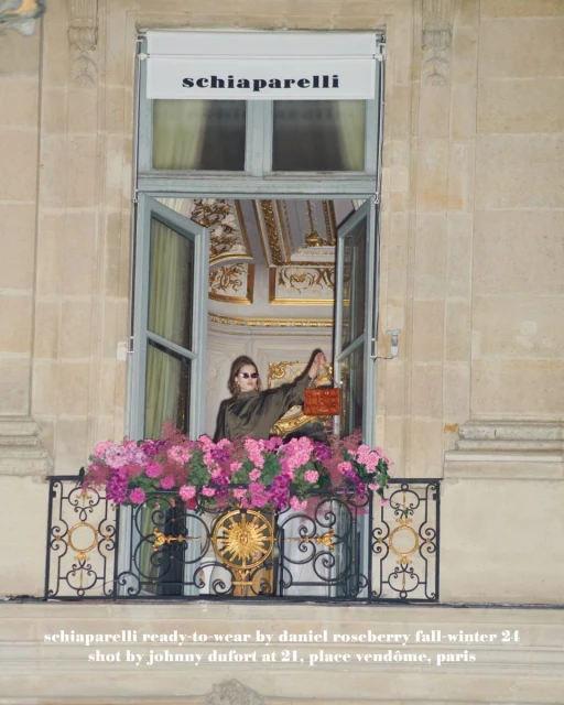 Adult female poses in window with flowers and orange purse, Schiaparelli ready-to-wear fall-winter 24, Place Vendôme, Paris.