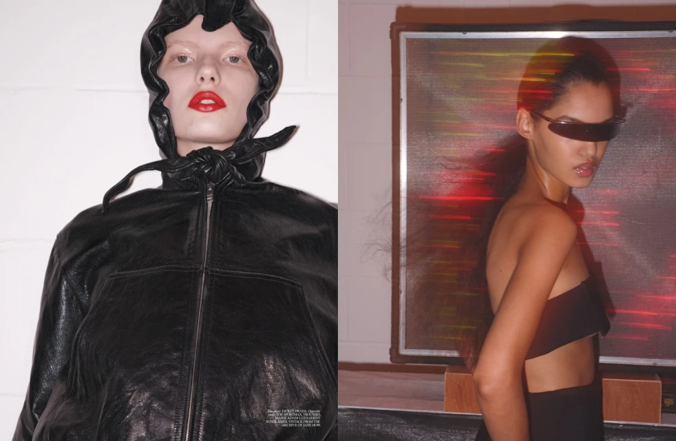 Two fashion models pose indoors: one in a black hooded jacket with red lipstick, and the other in a black top and futuristic sunglasses.