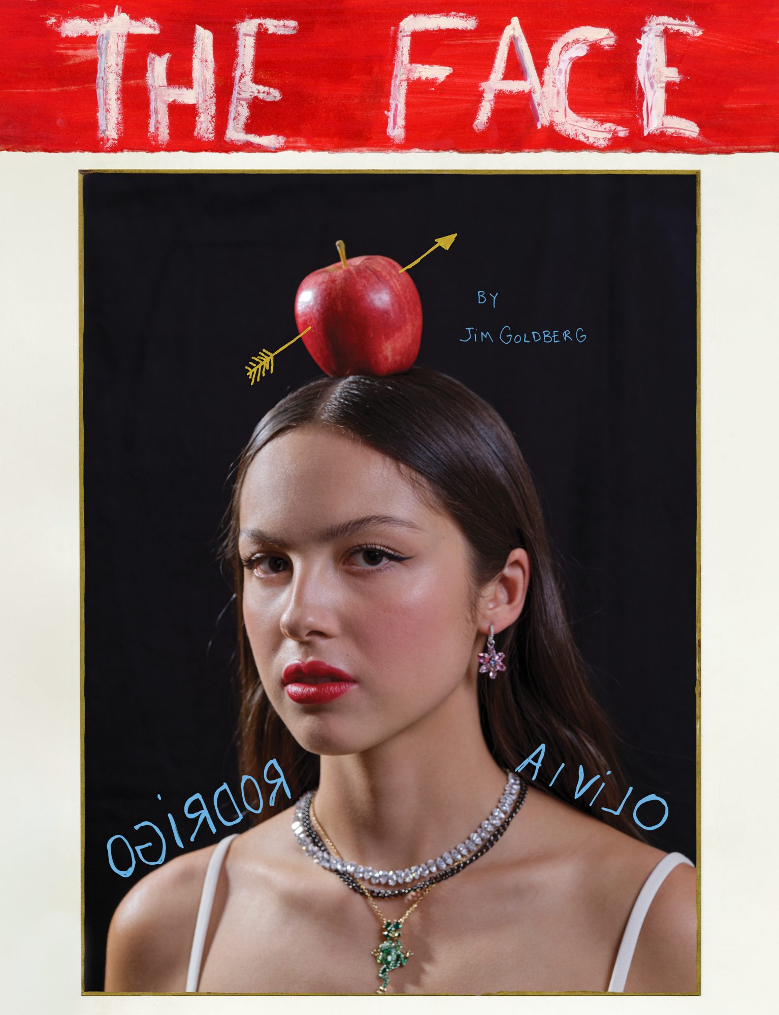 Close-up portrait of Olivia Rodrigo against a black backdrop, featuring a red apple balanced on her head pierced by a golden arrow.