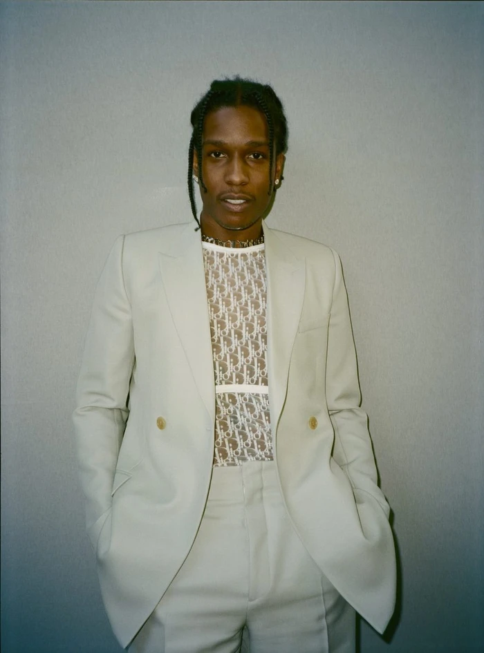 Portrait of ASAP Rocky wearing a cream double-breasted suit and monogrammed sheer top by Hugo Scott