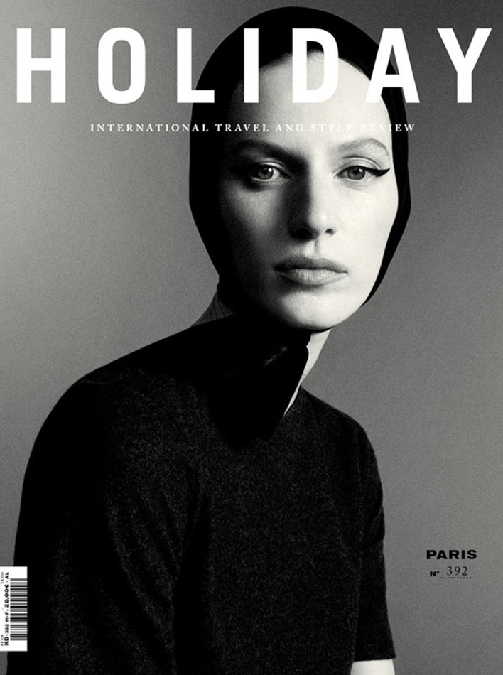 Holiday Magazine cover featuring a fair-skinned woman in black head covering and short-sleeved top against a gray backdrop.
