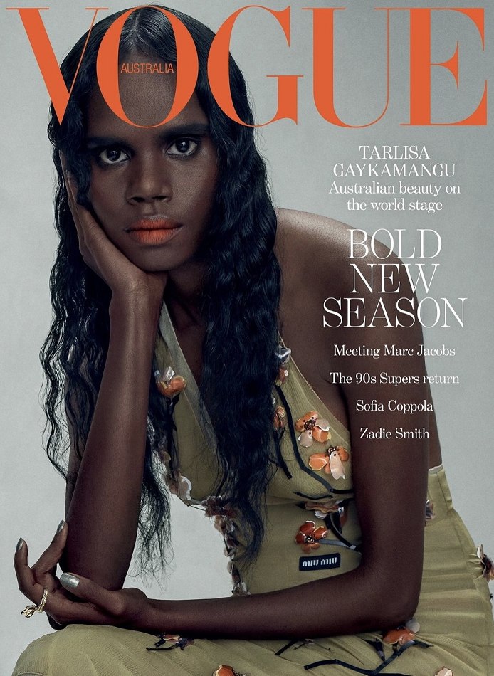 Vogue Australia cover featuring a woman with dark hair wearing a light green dress with flower embellishments, posing with her hand to her face.