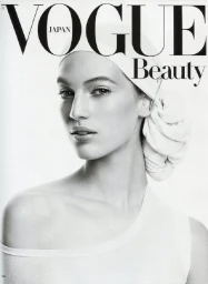 Close-up black and white editorial portrait of a female model wearing a white towel wrap on her head and a white top