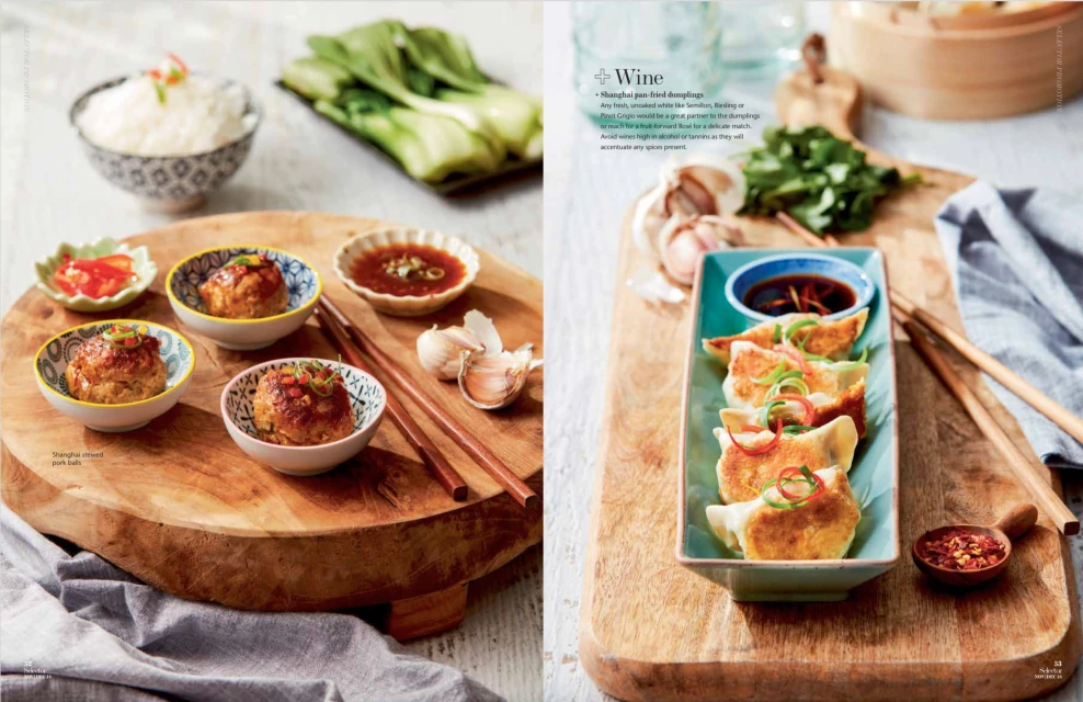 Overhead shot of two wooden boards featuring various Asian dishes, including steamed pork balls, dumplings, and accompanying sauces.