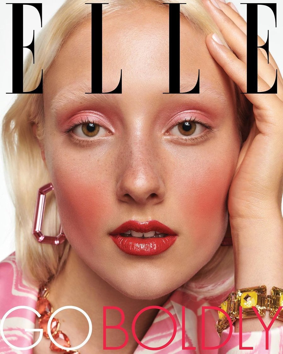 Elle magazine cover featuring a young woman with blonde hair and red lipstick, wearing pink jewelry and a matching top, striking a pose.