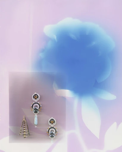 Still life of white gold earrings and cone sculpture against a backdrop of soft pink hues and a blurred blue floral shape.