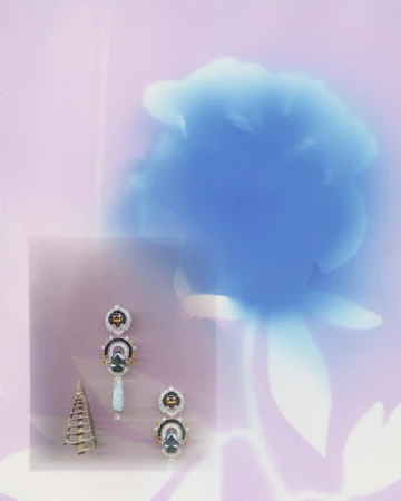 Still life of white gold earrings and cone sculpture against a backdrop of soft pink hues and a blurred blue floral shape.
