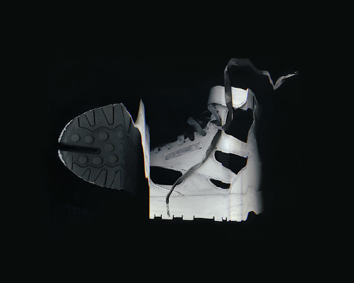 High-top Reebok sneaker cut in half, showing sole and shoe profile, illuminated against a black background.
