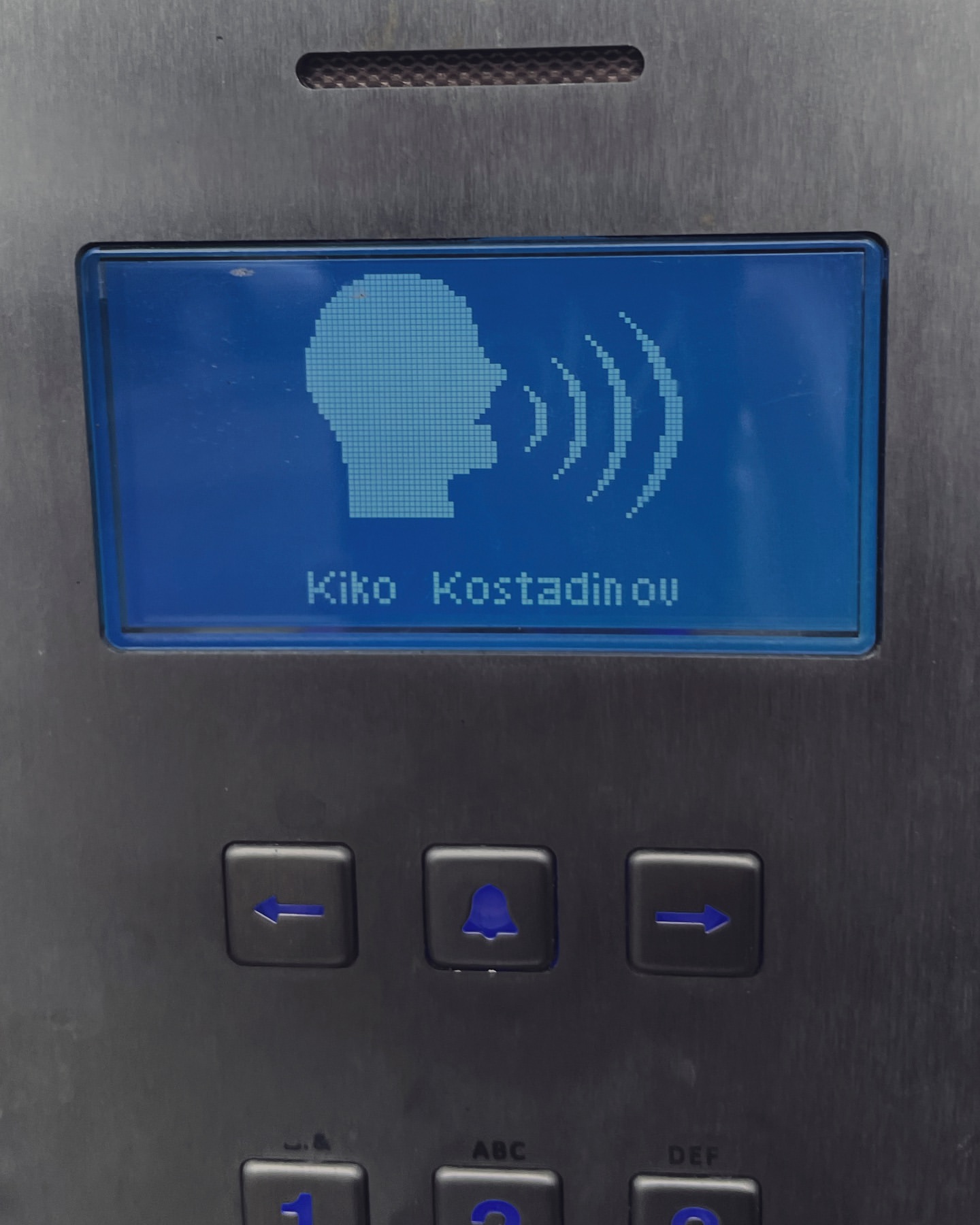 Electronic sign displays Kiko Kostadinov's name alongside a head icon with sound waves on a control panel.