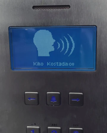 Electronic sign displays Kiko Kostadinov's name alongside a head icon with sound waves on a control panel.