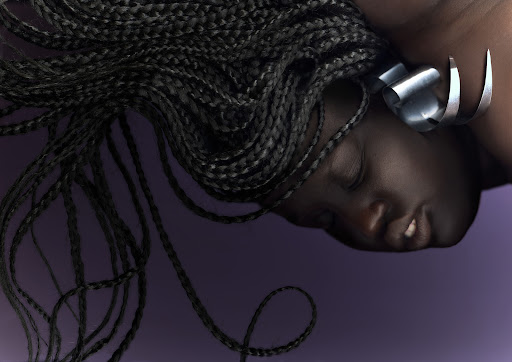 Portrait of a Black woman with braided hair and large silver earrings against a purple background, showcasing beauty and fashion.