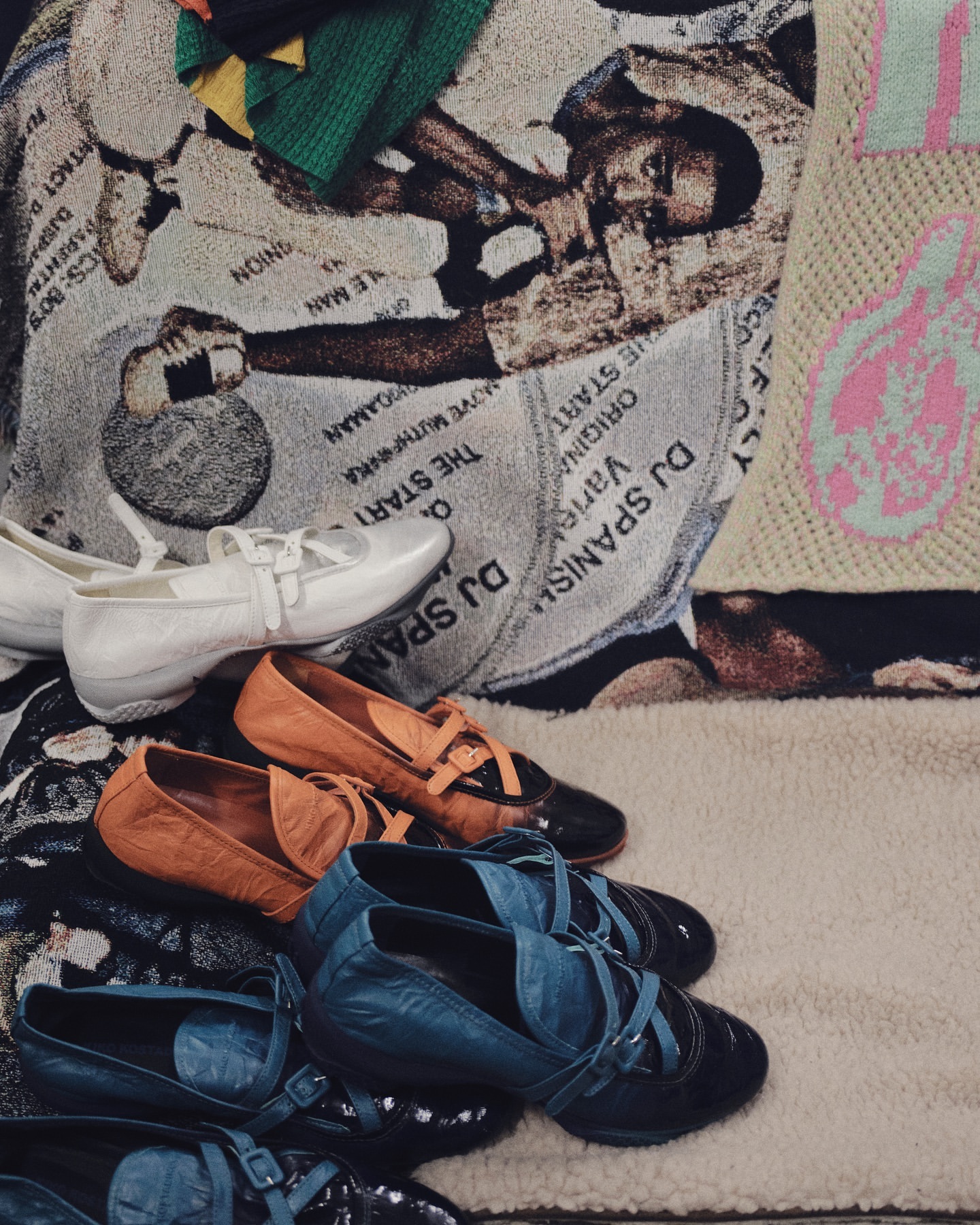 A close-up shot showcases an assortment of ballet shoes in white, brown, blue, and black, resting on a patterned surface.