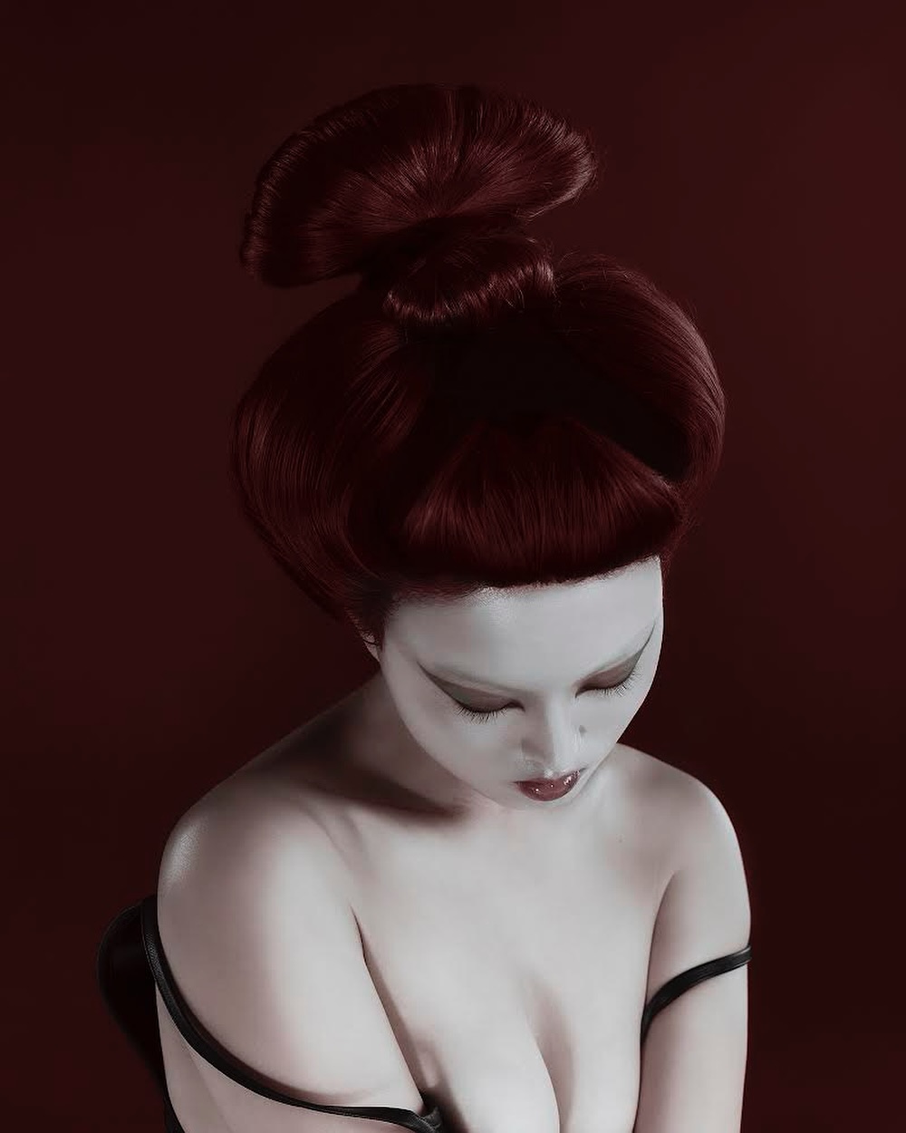Woman with pale skin and high auburn hairstyle poses against a dark red background in a portrait. Beauty and fashion editorial.