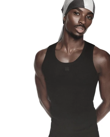 Black man wearing a black ribbed tank top and a striped headscarf against a plain white background