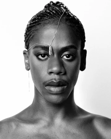 Close-up portrait of a Black subject with braided hair and a fine silver chain across the forehead, directed by Alex Black.