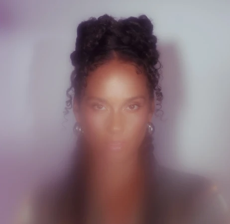 Portrait of a woman with braided updo hairstyle and silver hoop earrings against a soft glowing white background