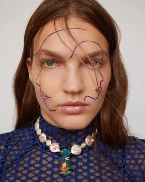 Close-up portrait of a woman with a pearl necklace and line art on her face against a neutral background, showcasing fashion and beauty.