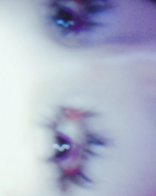 Close-up of a fair-skinned person's face with open mouth, showing teeth and the blurred view of an eye in a blurred, light-filled scene.