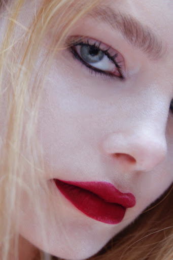 Close-up beauty portrait of a woman with bold red lips and dark eyeliner by photographer Anairam.