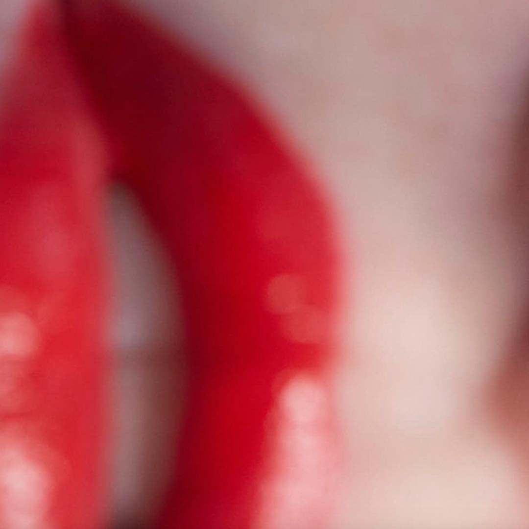 Close-up abstract of shiny red lipstick and pale skin, out of focus, beauty and fashion.