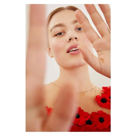 Close-up portrait of a woman with red floral appliqued dress, holding hand up near lens by Anairam