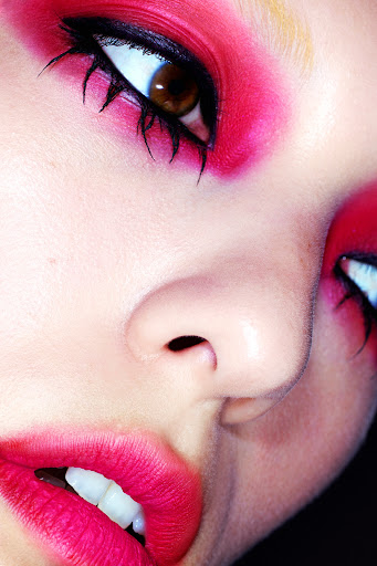 Extreme close-up macro portrait of a model with vibrant pink eye makeup, black winged eyeliner, and bright pink lips.