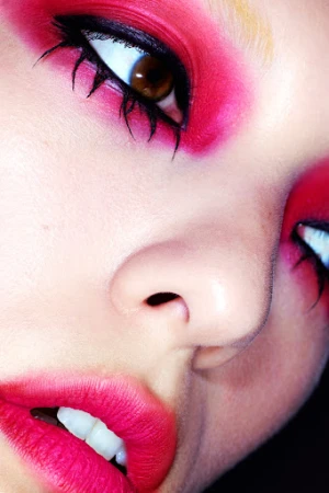 Extreme close-up macro portrait of a model with vibrant pink eye makeup, black winged eyeliner, and bright pink lips.