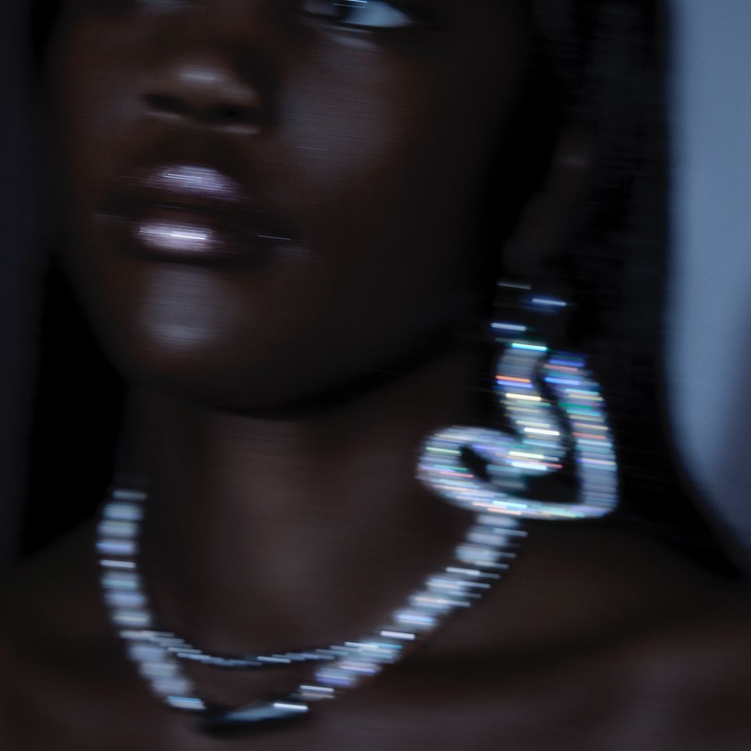 Close-up studio portrait of an African-American woman wearing a pearl necklace and heart-shaped earrings, soft focus, and dark lighting.