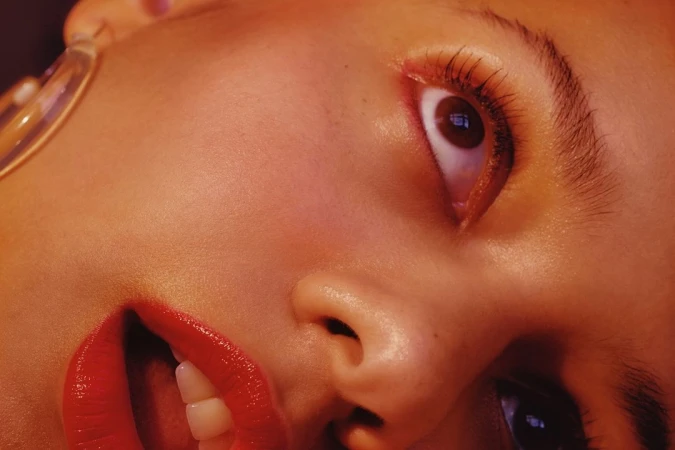 Close-up studio portrait of a woman with brown eyes and red lipstick in warm lighting, showcasing beauty and photographic technique.