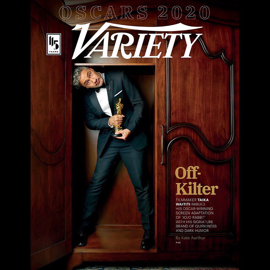 Taika Waititi poses in a wooden wardrobe holding an Oscar for Variety magazine, Oscars 2020 issue, wearing a suit with a bow tie.