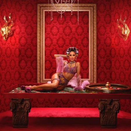 Elegant woman in lingerie and hair rollers poses on a roulette table in a red-toned room with ornate decor and dramatic lighting.