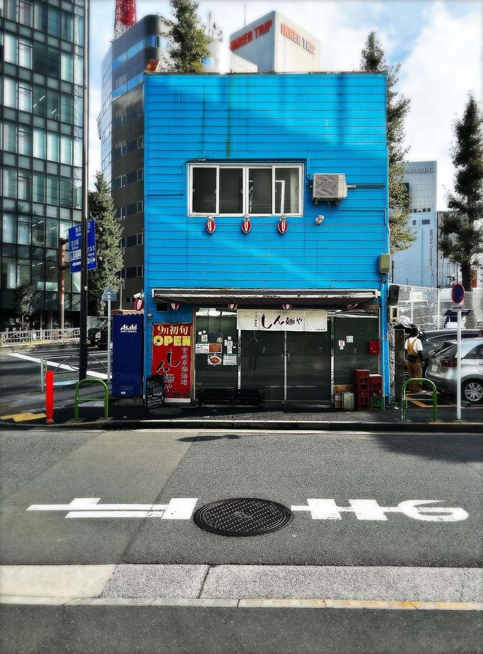 A charming blue building stands on a city street with a distinctive Japanese storefront, a glimpse into Tokyo's unique architectural landscape.