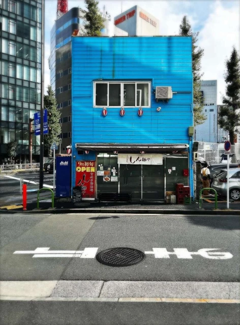 A charming blue building stands on a city street with a distinctive Japanese storefront, a glimpse into Tokyo's unique architectural landscape.