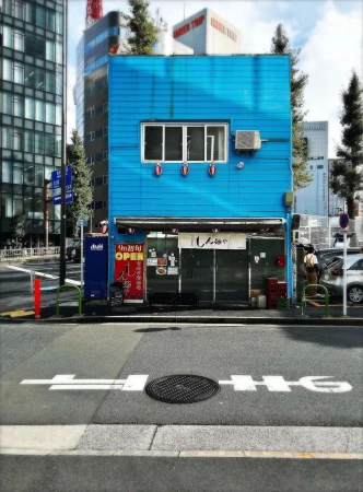 A charming blue building stands on a city street with a distinctive Japanese storefront, a glimpse into Tokyo's unique architectural landscape.