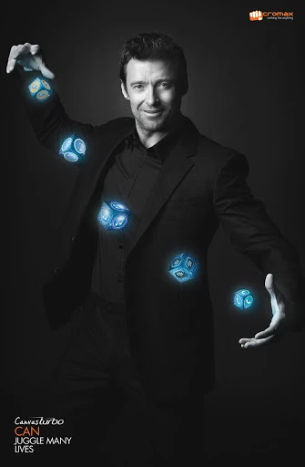 Promotional shot of Hugh Jackman in a black suit juggling glowing blue cubes against a dark gray background, advertising Micromax Canvas Turbo.