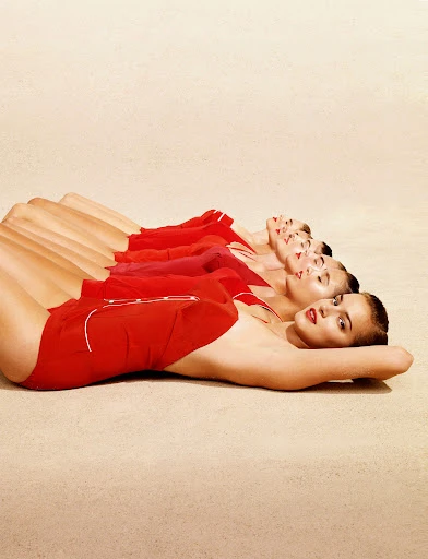 Multiple images of a woman in a red swimsuit lying on a beige surface, creating a surreal, repetitive, yet artistic visual effect.