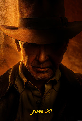Close-up promotional image of Harrison Ford as Indiana Jones wearing a fedora and jacket against a warmly-lit background.
