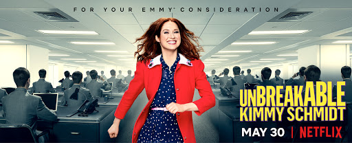 Unbreakable Kimmy Schmidt promo image. A woman smiles and walks towards the camera in an office full of workers at desks with computers.
