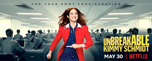 Unbreakable Kimmy Schmidt promo image. A woman smiles and walks towards the camera in an office full of workers at desks with computers.