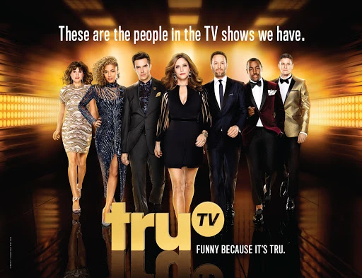 Group of seven adults stand in a studio with warm lighting, wearing suits and dresses. truTV logo present at the bottom.