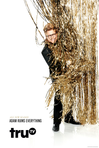 Promotional shot for the television show Adam Ruins Everything, featuring Adam Conover partially visible behind gold streamer curtains.