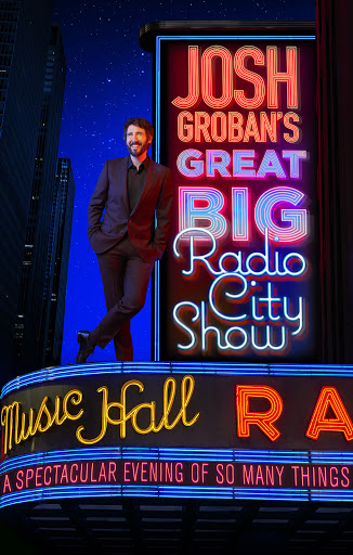 Josh Groban stands next to a neon sign for his 'Great Big Radio City Show' in front of a high-rise building at night with stars.