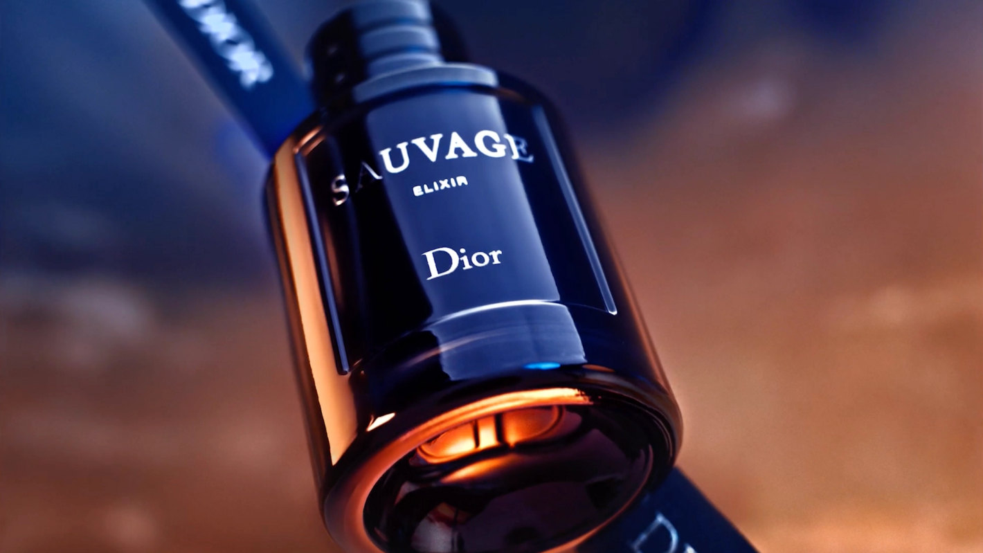 Close-up of a sleek, dark blue Dior Sauvage Elixir perfume bottle, emphasizing its elegant design and the interplay of light and shadow.
