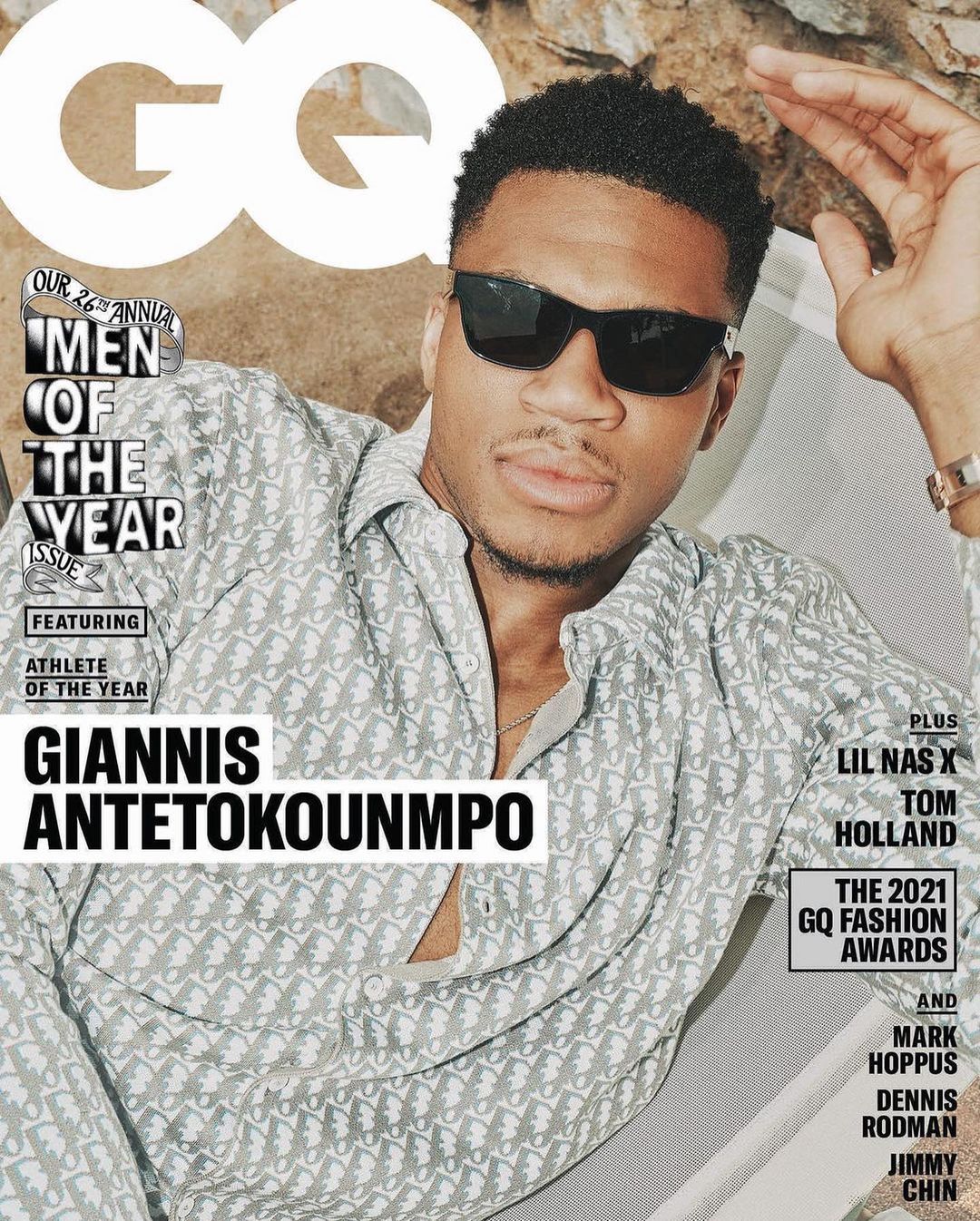 GQ magazine cover featuring Giannis Antetokounmpo in sunglasses and patterned shirt, posing outdoors with rock background and magazine text.