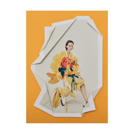 Art photograph of a woman wearing a yellow dress on top of a torn paper sheet over an orange background. Fashion and creative portrait.