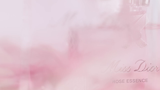 Close-up of Miss Dior Rose Essence perfume bottle with silver text on a soft pink background, product shot for beauty and fashion.