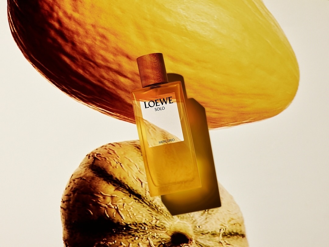 Loewe Solo Mercurio perfume bottle stands out against a backdrop of yellow fruit slices in a minimalist commercial setting.